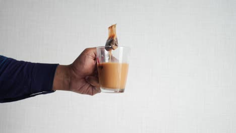 person holding a cup of tea with a tea bag