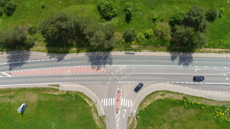 static top down aerial view of countryside road traffic and intersection on sunny summer day, high angle drone shot