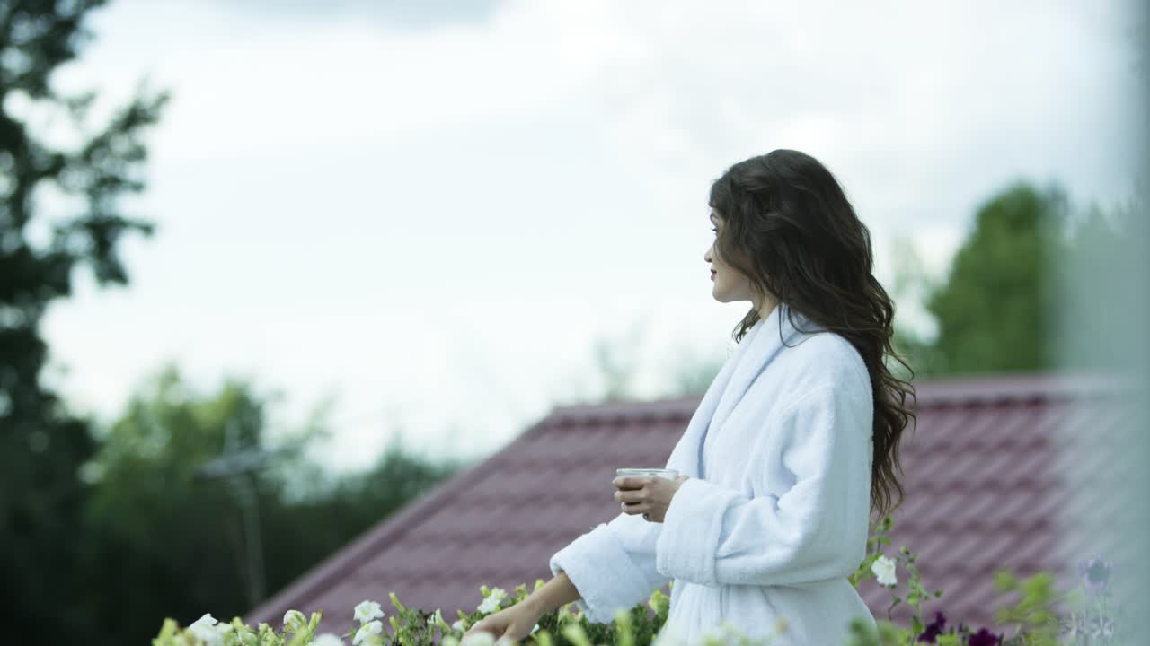 욕조 를 입은 여자 가 발코니 에서 휴식을 취하고 있다