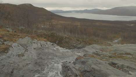 water flows towards lake in mountain view in slow motion