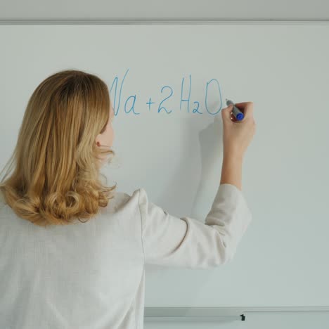 teacher writes chemistry formulas on the board solves the equation