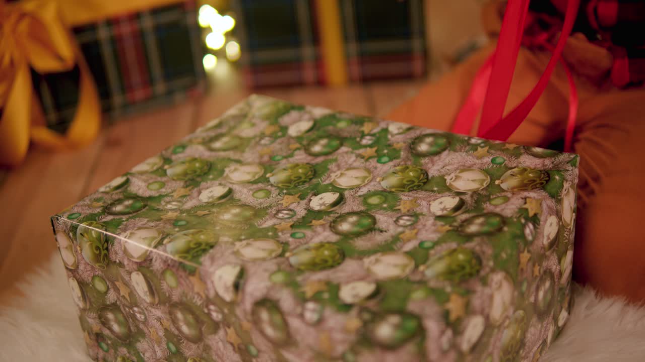 어린 소년이 무릎을 꿇고 거대한 크리스마스 선물의 빨간 리본을 당기고 있다