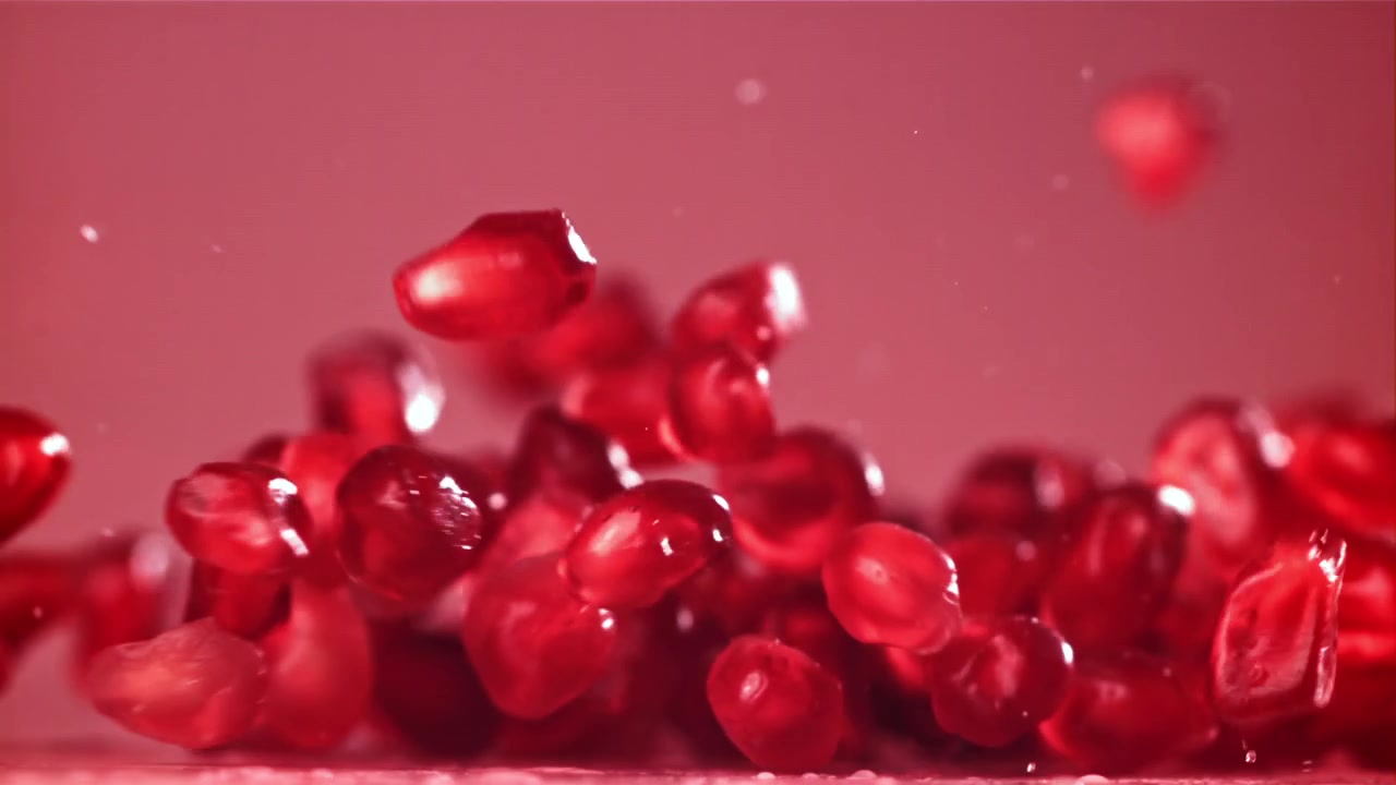 Levende røde granatæblekerner falder i slowmotion