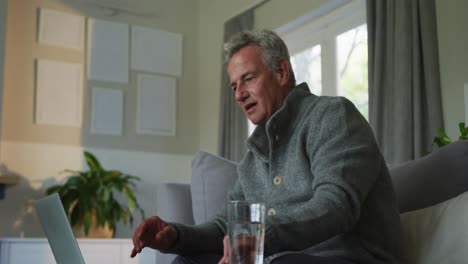 Caucasian-senior-man-doing-paperwork-and-using-laptop-at-home