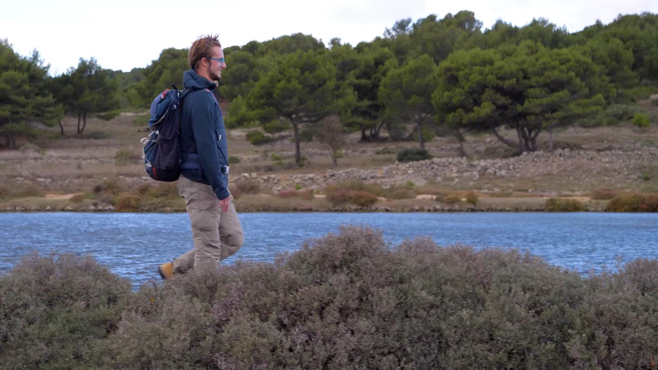 paralaje en cámara lenta de un hombre caminando a lo largo de un lago cerca de las llanuras de sal de sete
