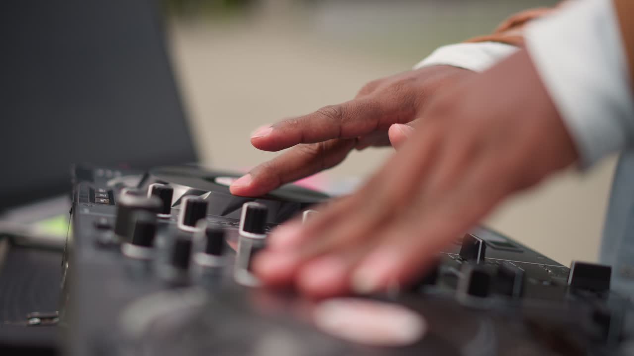 dj mixing on controller park walkway closeup fingers on jog and fader, laptop open, red cable, casual jacket, bench backdrop, precise fingerwork and rhythmic beat, solo busker performance vibe