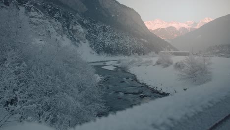 Río-En-El-Paisaje-Invernal,-Altas-Montañas-Alpinas-En-El-Fondo