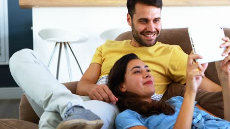 Lächelndes-Paar-Mit-Digitalem-Tablet-Auf-Dem-Sofa-Im-Wohnzimmer