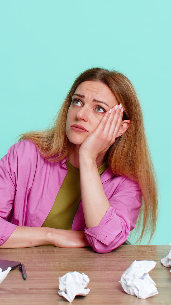 Angry woman sitting at table crumpling paper in frustration after mistake in report failed solution