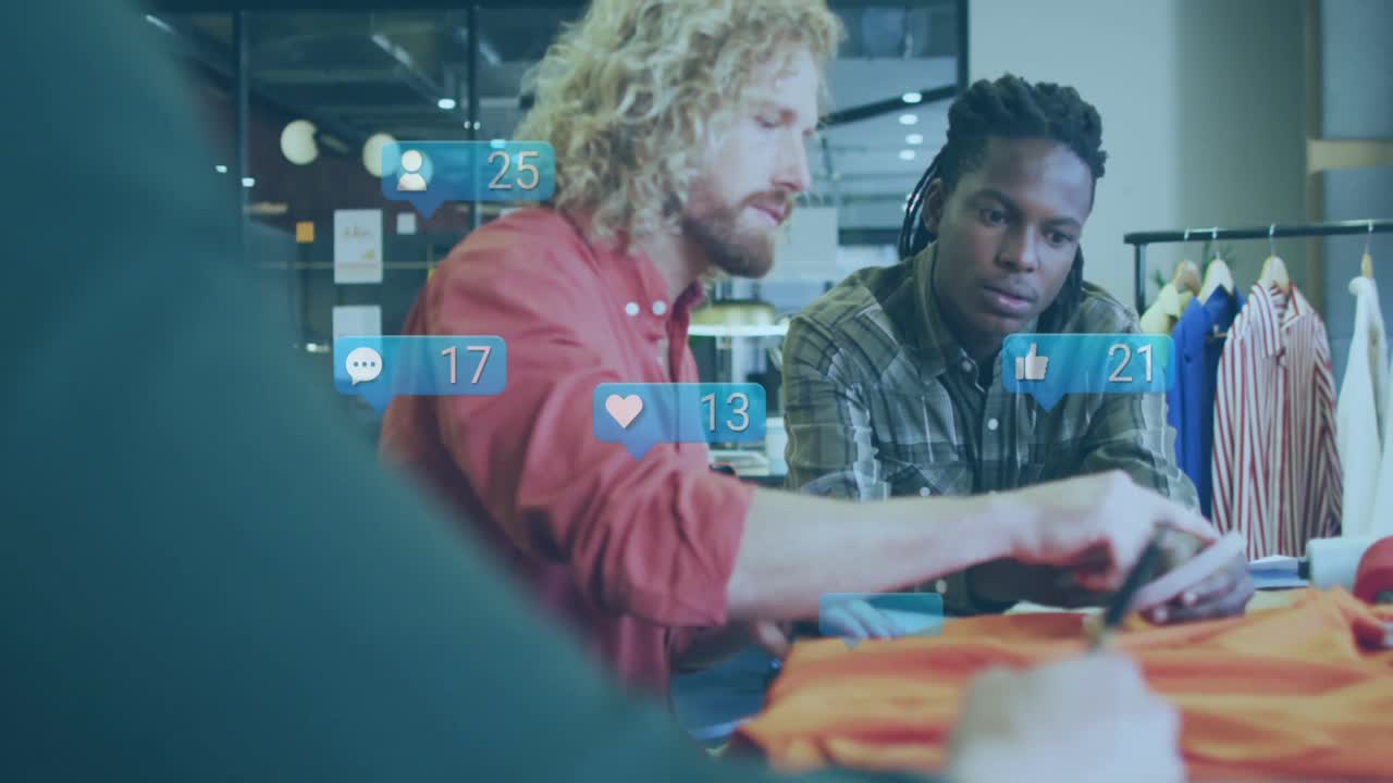 Animation of social media icons floating over two diverse male photographers discussing at studio