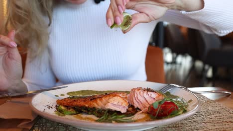 woman eating grilled salmon dinner in a restaurant