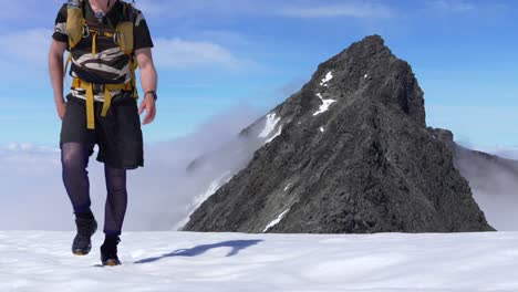 Toma-Estática-De-Un-Hombre-Acercándose-A-La-Cámara-Mientras-Hace-Montañismo-Por-Encima-De-Las-Nubes-En-Noruega.