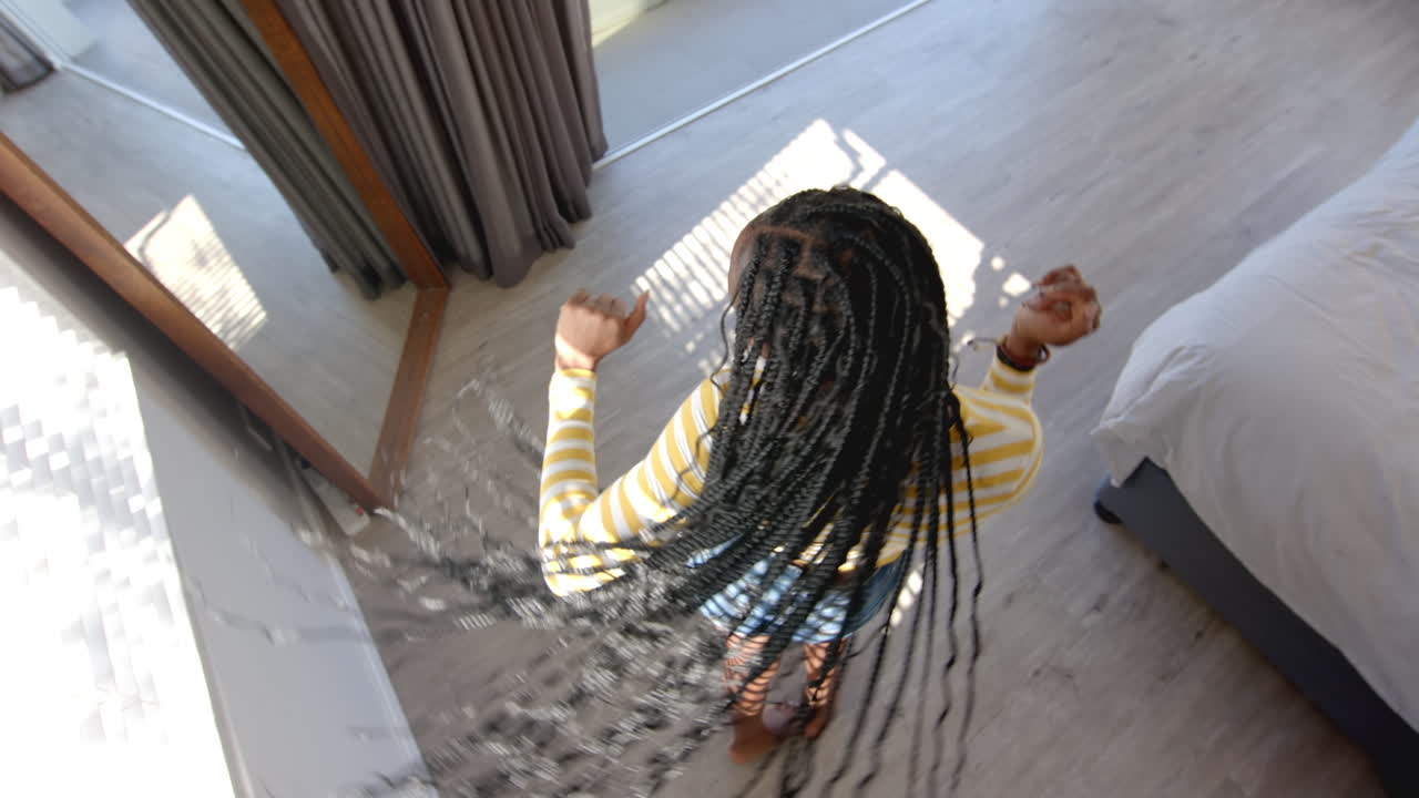 A young African American woman wearing striped outfit is reaching down, at home
