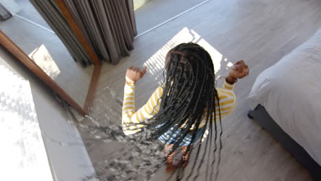 a young african american woman wearing striped outfit is reaching down, at home