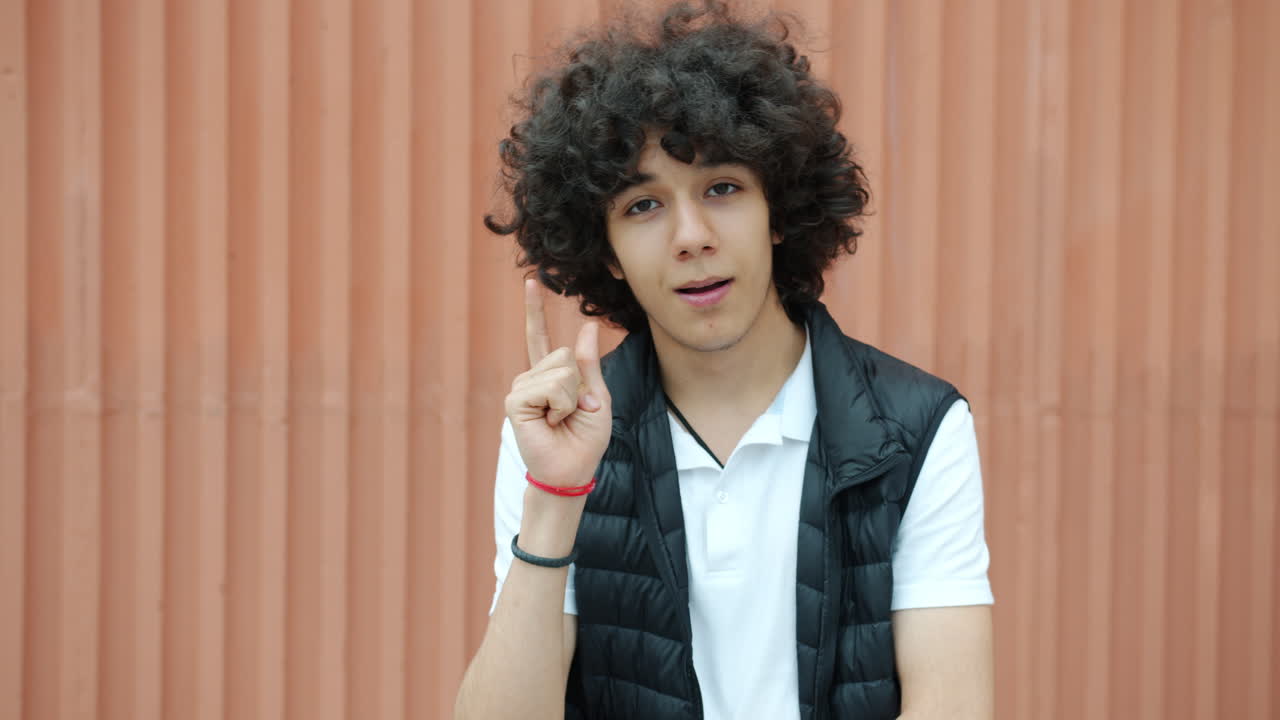 Teenager with curly hair, pointing upward