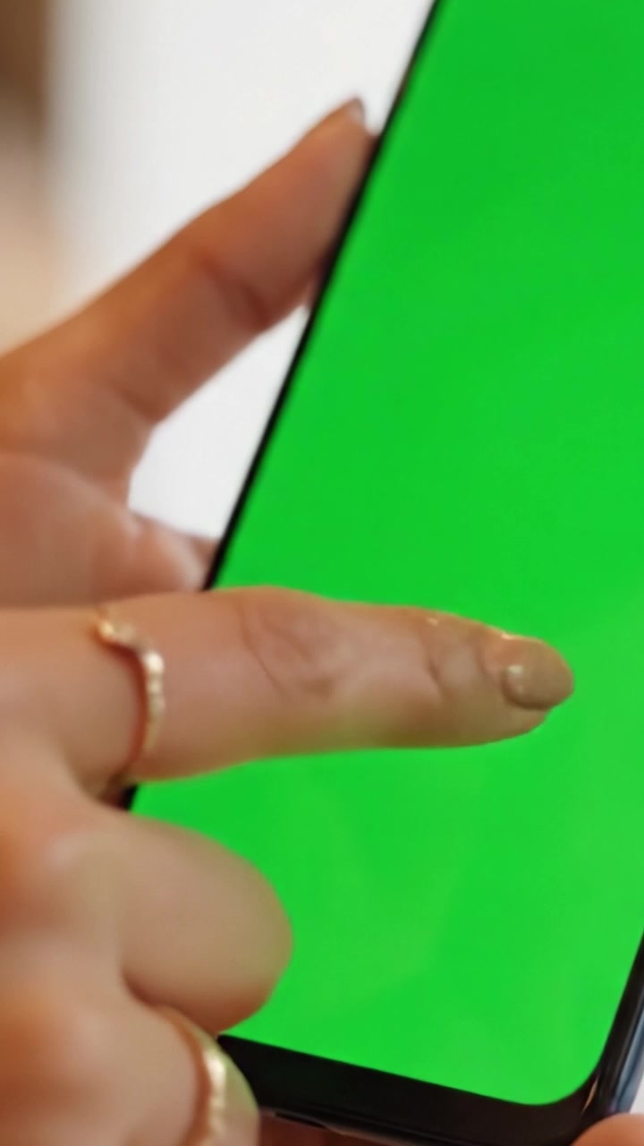 Primo piano di una mano che tiene uno smartphone con uno schermo verde brillante, ideale per display digitali, test di app o sfondi per effetti visivi.