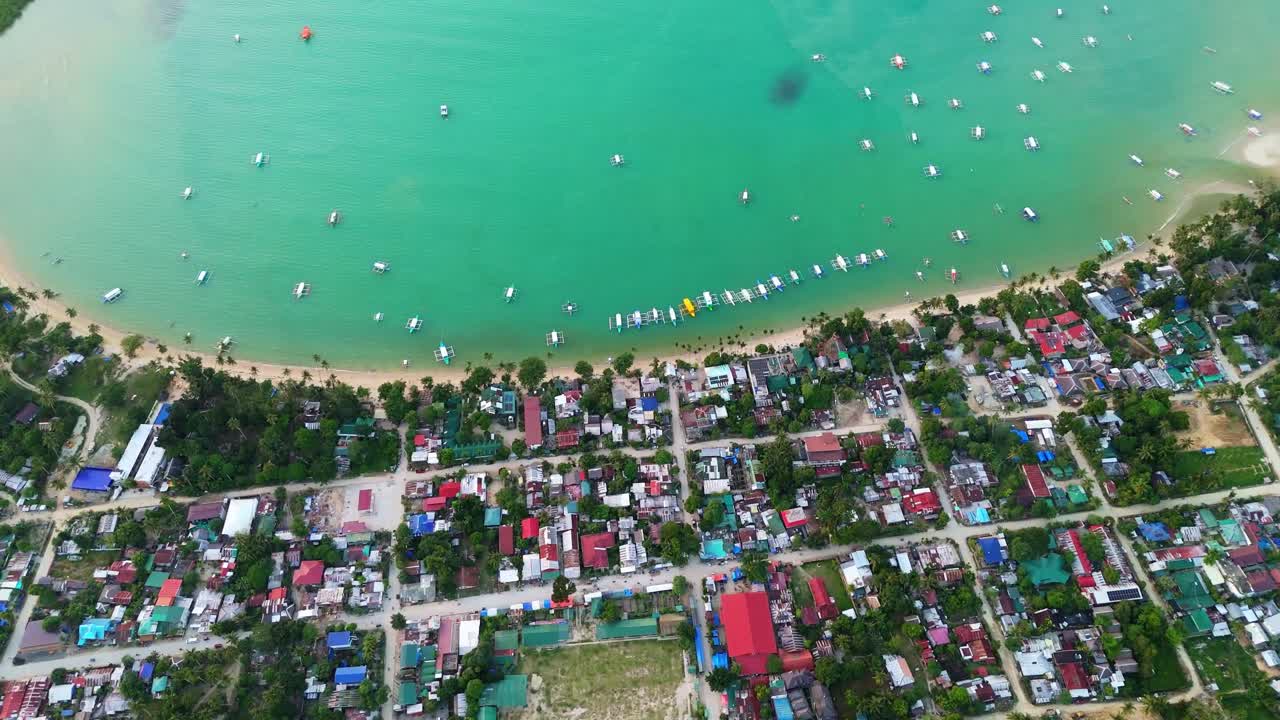 Inquadratura da drone della città costiera di Port Barton, con una spiaggia di sabbia bianca e acque turchesi cristalline, e numerose imbarcazioni a Palawan, Filippine. Vista tropicale.