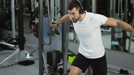 bodybuilder guy in gym pumping up hands in headphones from the sides