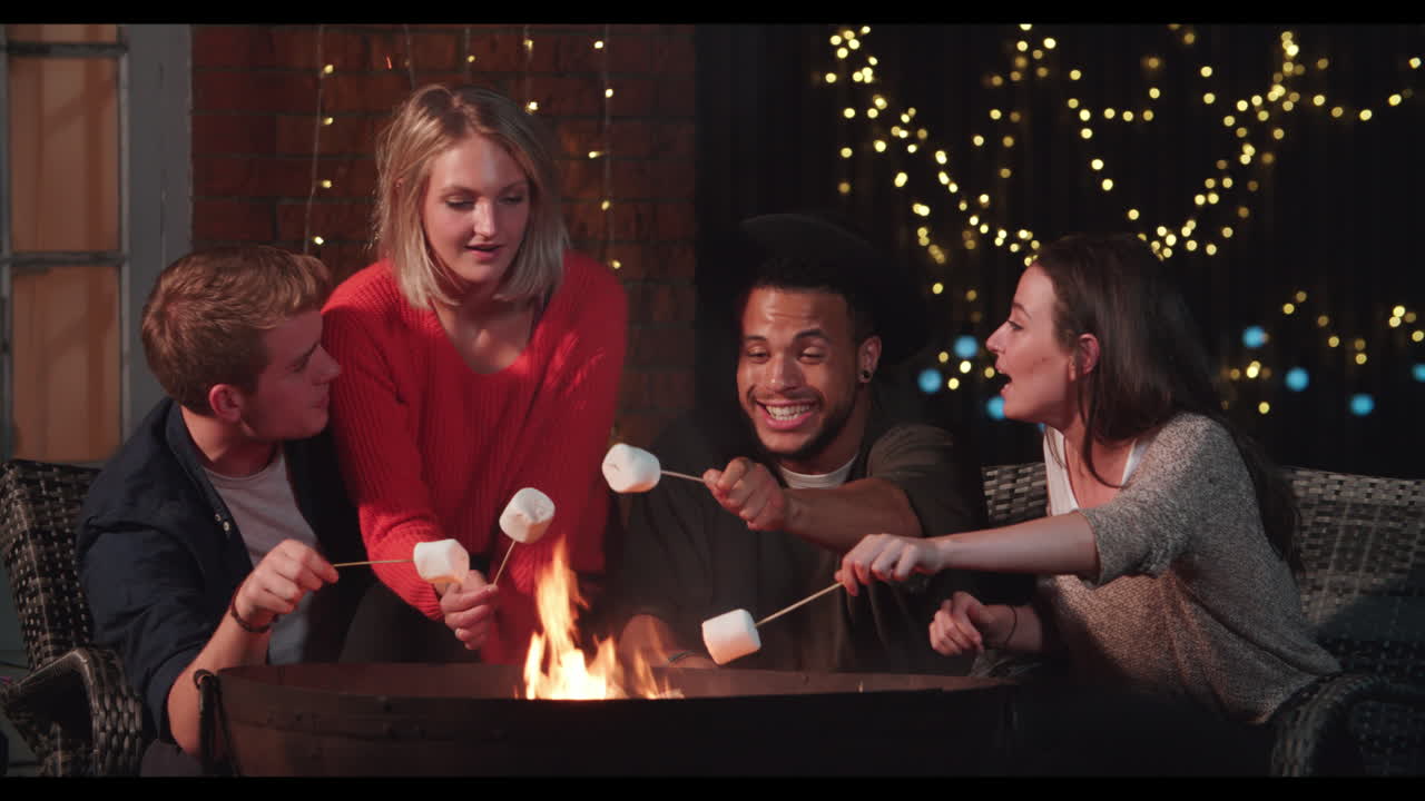 grupo de amigos tostando malvaviscos junto a la chimenea