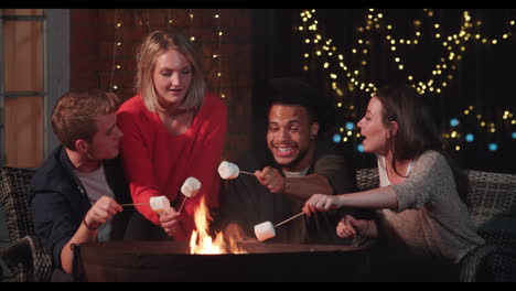 grupo de amigos tostando malvaviscos junto a la chimenea