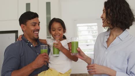 familia hispana feliz con una hija tomando un batido verde