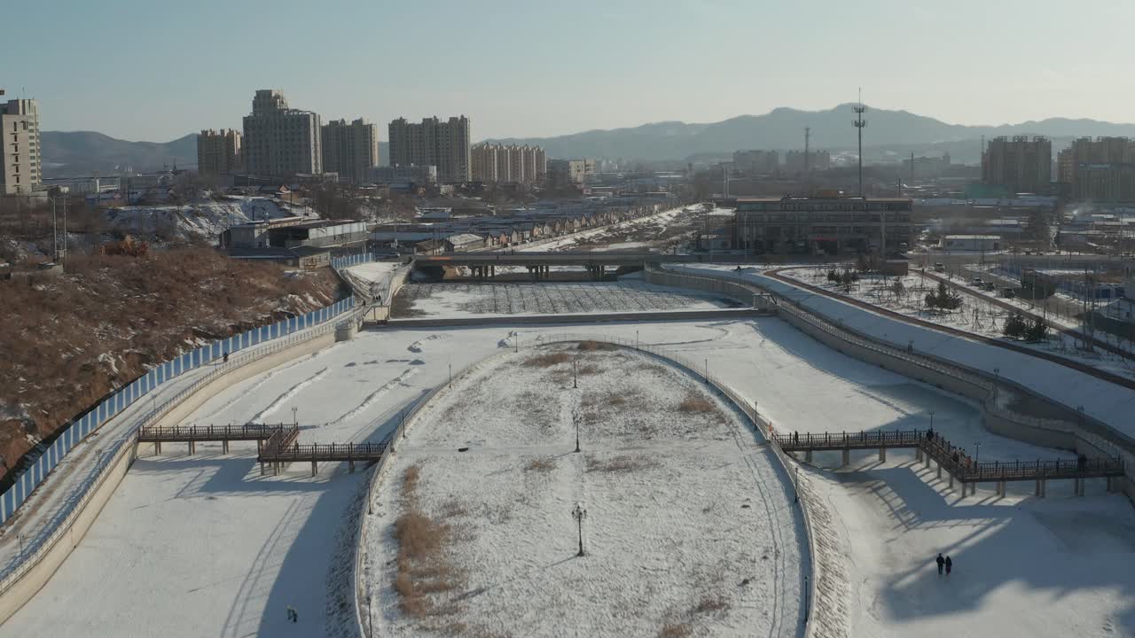 Rapid aerial rising shot of families enjoying winter recreation on frozen river. 4K