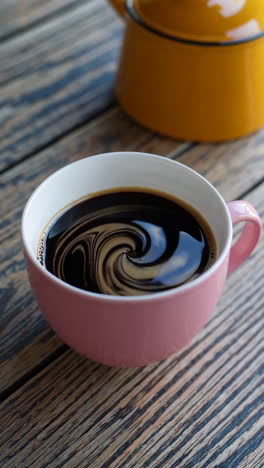 black coffee in a pink mug on a wooden table