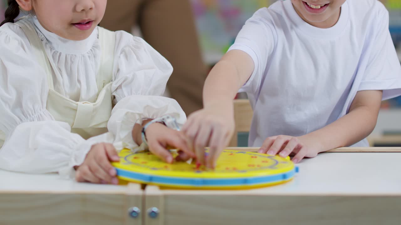 Dua Anak Memainkan Mainan Jam Warna-warni di Kelas yang Ceria