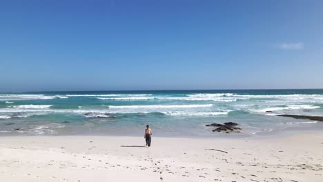 Chica-Caminando-Hacia-El-Mar-Sobre-Arenas-Blancas-De-Playa-Sudafricana---Toma-Aérea