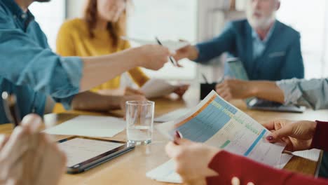 in the meeting room young and beautiful female junior associate makes a speech / report to a board of directors member who are sitting at the conference table. modern unicorn startup in the stylish office