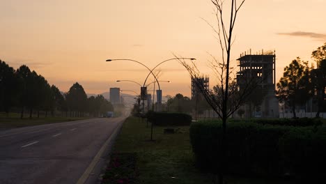 a beautiful cinematic morning view of islamabad with a yellowish sky with sunrise and buildings under construction on margalla road with no people