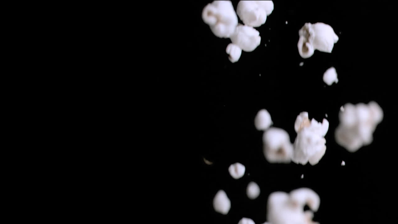 Animasjon av nærbilde av fallende popcorn mot kopieringsplass på svart bakgrunn