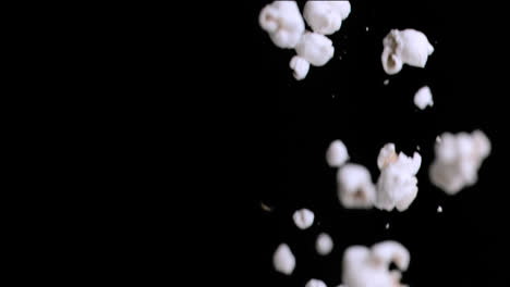 animation of close of popcorn falling against copy space on black background