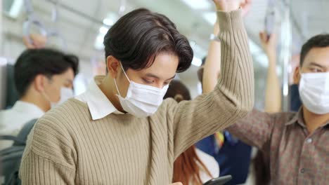 traveler wearing face mask while using mobile phone on public train