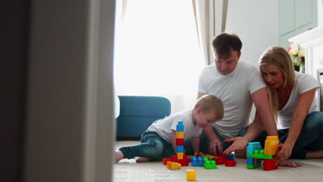 happy family dad mom and baby 2 years playing lego in their bright living room. slow-motion shooting happy family