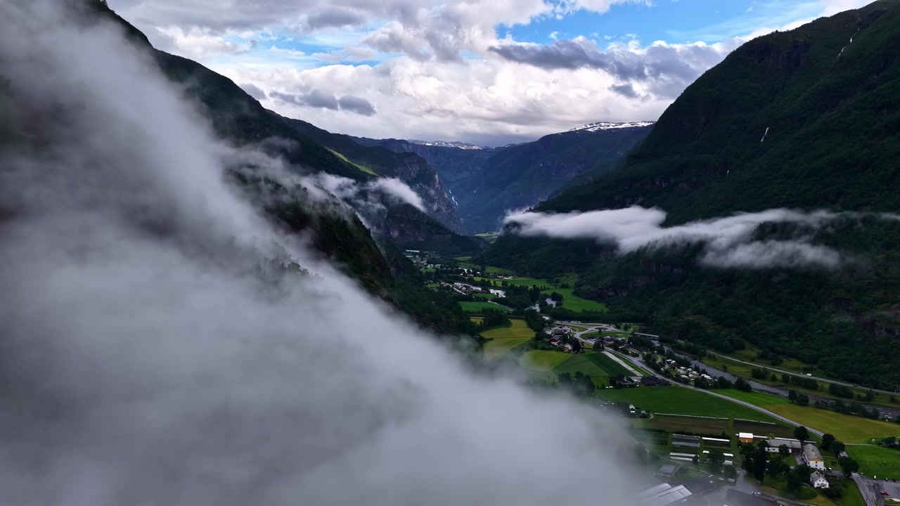 Wolken ziehen durch ein Fjordtal über einer grünen Landschaft in Aurland, Norwegen, statische mittlere Zeitrafferaufnahme.
