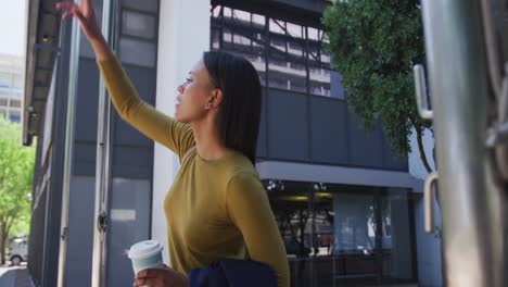 Mujer-Afroamericana-En-La-Calle-Sosteniendo-Café-Y-Levantando-La-Mano-Para-Detener-Un-Taxi