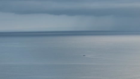 small boat in front of dark clouds in the pacific