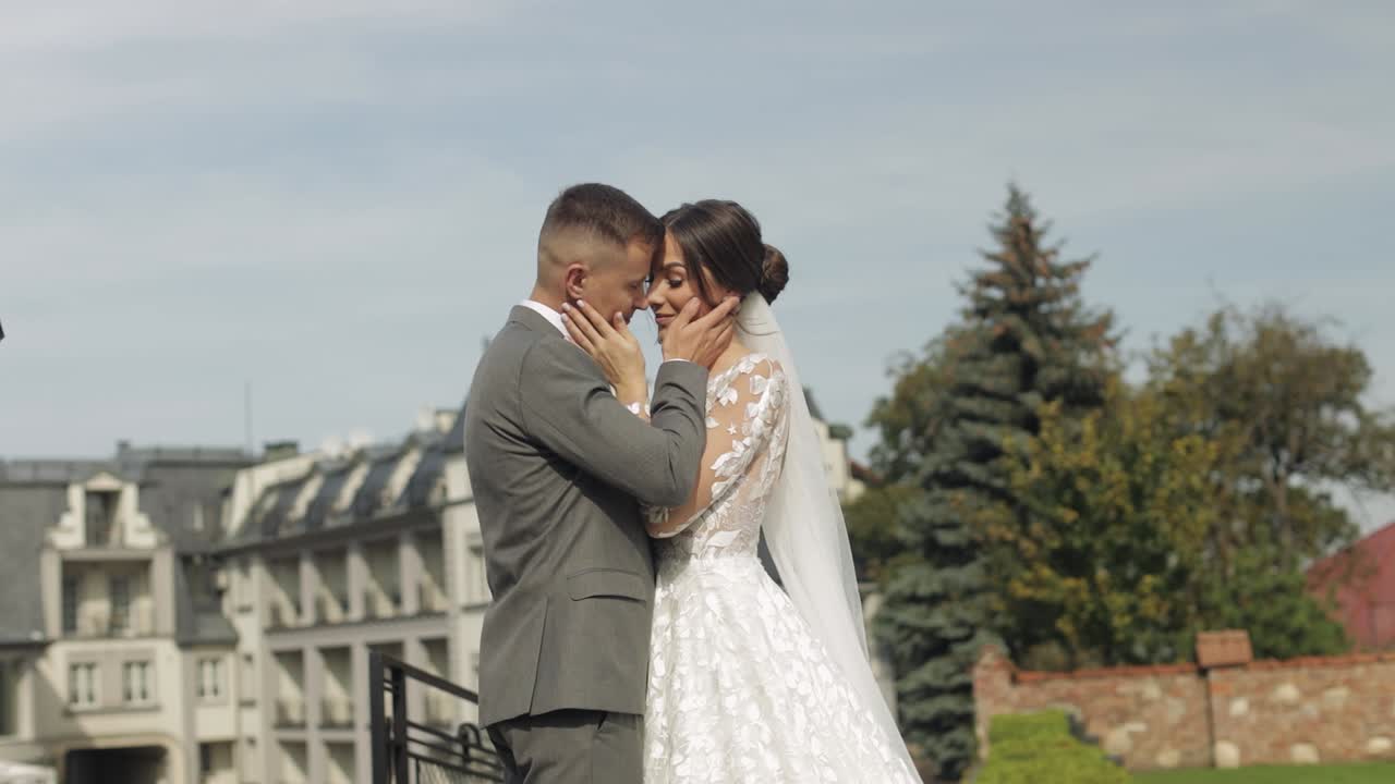 Lovely newlyweds caucasian bride embracing groom in park making kiss, wedding couple family hugging
