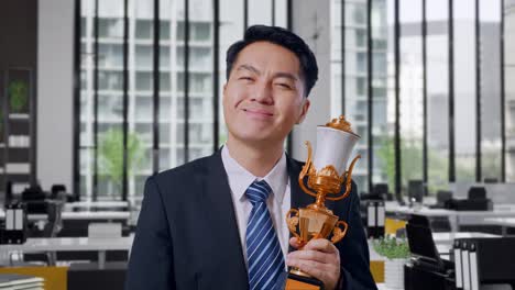 businessman holding trophy in office