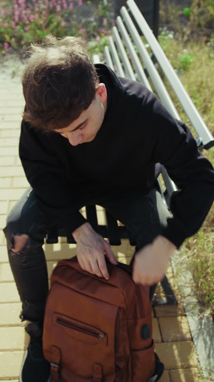 Man Closing His Notebook At The Park And Putting It In The Backpack