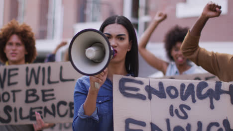 grupo diverso de hombres y mujeres con pancartas gritando usando megáfono durante la protesta