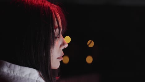 beautiful young woman is sad and has her eyes closed. filmed from the side close up at night