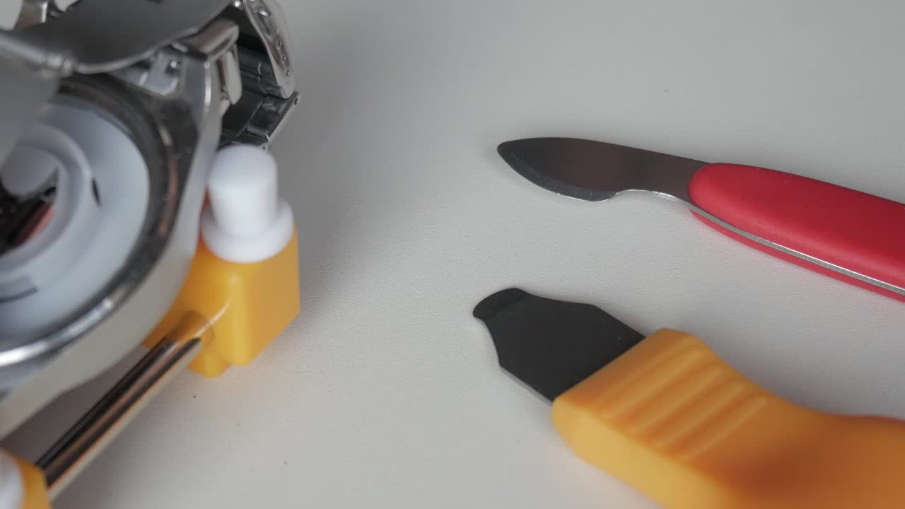 Close-up of watch repair tools in use on a white table
