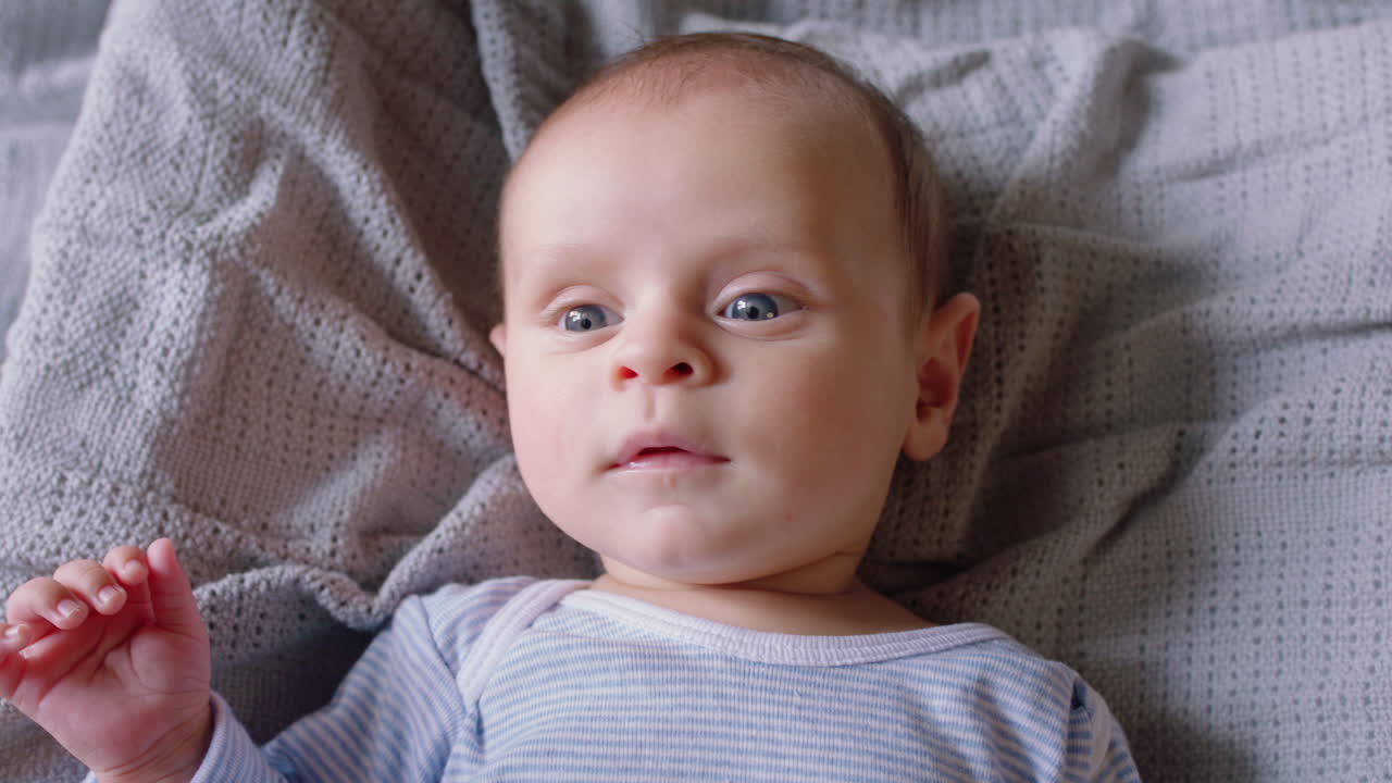retrato de un bebé feliz buscando un bebé curioso acostado en una manta