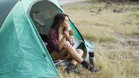 happy pensive camping girl drinking coffee from metal mug