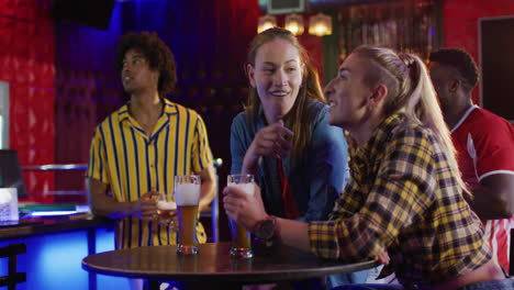 video of diverse group of happy friends drinking and watching sports game at a bar, celebrating