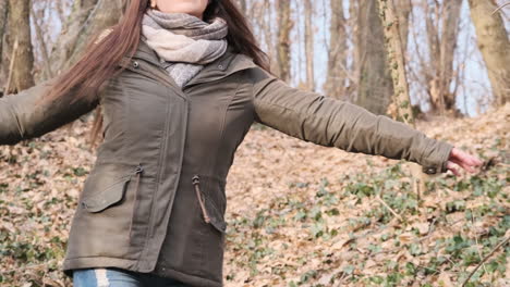 mujer con cabello castaño bailando en medio del bosque en un hermoso día soleado de invierno - tiro medio, cámara lenta