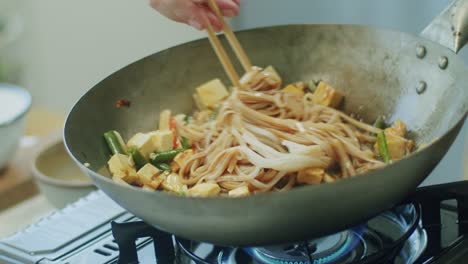 mujer mezclando deliciosos fideos de wok con palillos