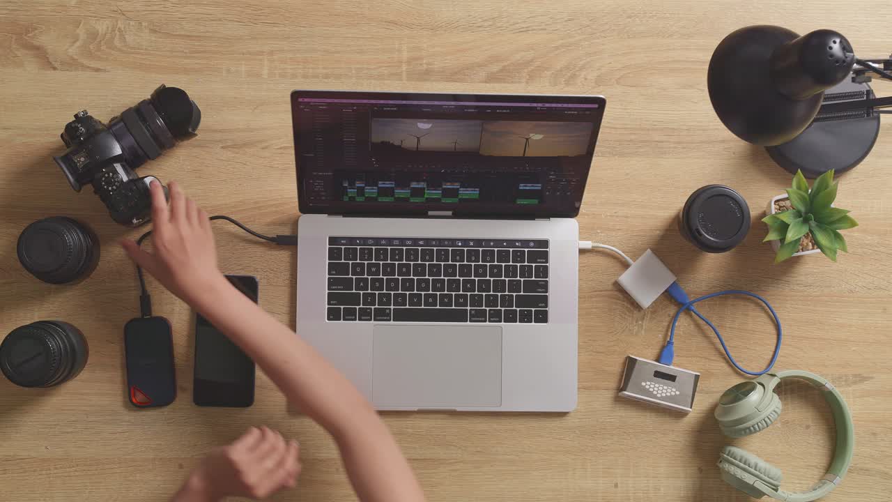 vista superior de cerca de las manos de la editora poniendo la tarjeta de memoria en una computadora portátil y luego eligiendo el video en el espacio de trabajo en casa
